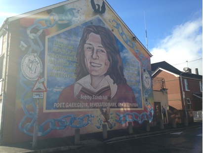 This is a Bobby Sands mural located on Falls Road. The mural says, “Everyone Republican or otherwise has their own particular role to play...our revenge will be the laughter of our children. Bobby Sands MP, Poet, Gaeilgeoir, Revolutionary, IRA Volunteer.”  Bobby Sands was a member of the IRA who died during a hunger strike along with nine other members of the IRA and INLA (Irish National Liberation Army) while jailed in HM Prison Maze. These deaths led to a resurance of activity during The Troubles.